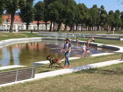 a man walking a dog in front of a fountain at Villa Domus XIX in Tongeren