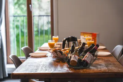 a wooden table with a basket of wine bottles on it at Vakantiewoning & Fietslogies VELO, rustig vlakbij Maastricht in Bilzen