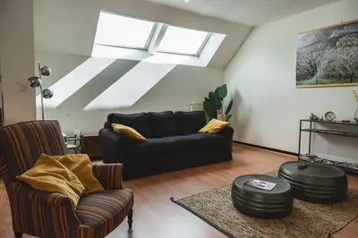 a living room with a couch and chairs and a skylight at Vakantiewoning & Fietslogies VELO, rustig vlakbij Maastricht in Bilzen
