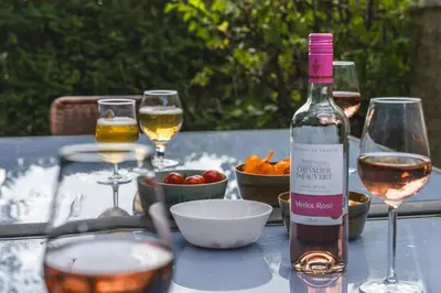 a bottle of wine and glasses on a table at Vakantiewoning & Fietslogies VELO, rustig vlakbij Maastricht in Bilzen