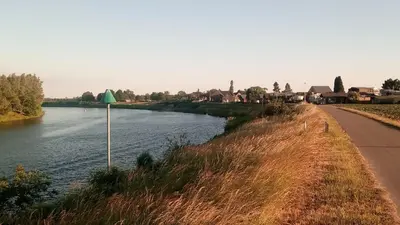 a road next to a river with a green umbrella at Maas Chalet Aldeneik in Maaseik