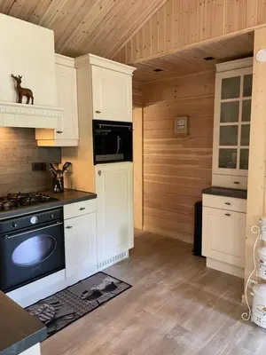 a kitchen with white cabinets and a black stove at Chalet Sint-Hubertus Deluxe in Zutendaal