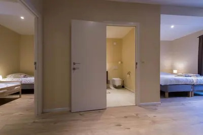 a room with two beds and a door leading to a bedroom at B&B 't Maanhof in Gingelom