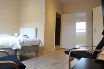 a bedroom with a bed and a table and chairs at B&B 't Maanhof in Gingelom