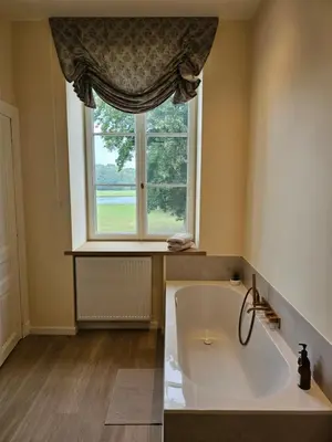 a large bath tub in a bathroom with a window at Kasteel Duras in Sint-Truiden