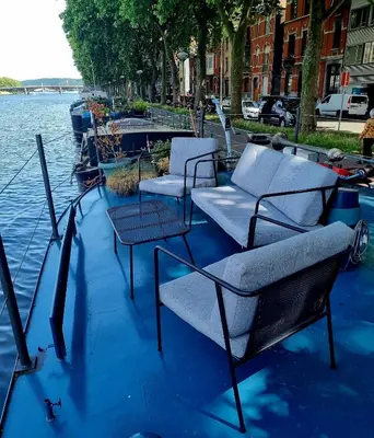 a group of chairs and tables on a boat in the water at La Cabine du Capitaine in Liège