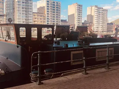 a boat sitting on aarf with buildings in the background at La Cabine du Capitaine in Liège
