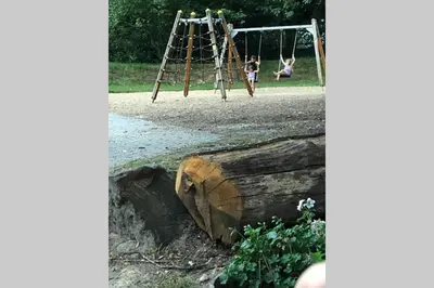 two children playing on a swing set in a park at Nieuw vebouwd Vakantie Boshuisje Meibloempje in Lanaken