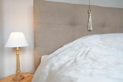 a bed with a white comforter and a lamp at Huize Idalie in Bilzen