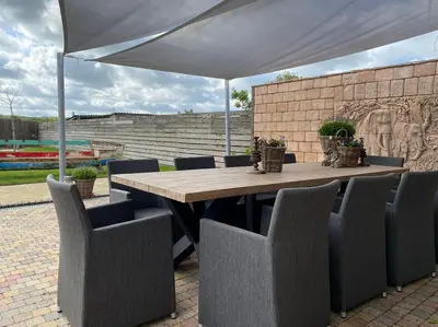 a wooden table and chairs under a white umbrella at Den 118, aan de Maas in Maasmechelen