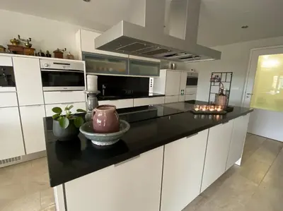 a kitchen with white cabinets and a black counter top at Den 118, aan de Maas in Maasmechelen