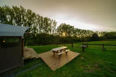 a wooden deck with a picnic table in a field at Le Relais d'Artagnan - relais équestre in Mortier