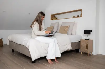a woman sitting on a bed with a laptop at Luna Logies in Lanaken