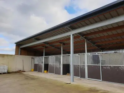 a large metal building with a bunch of stalls at B&B La ferme du Château de Broich in Plombières