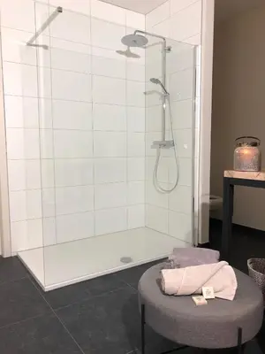 a bathroom with a shower and a stool with a towel at Huis Berenbroek in Genk