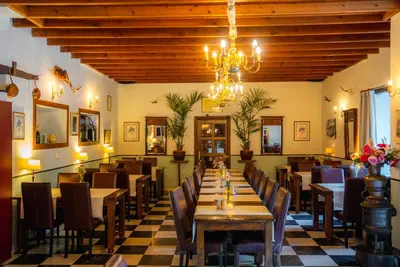 a restaurant with tables and chairs and a chandelier at Vakantie Logies de Kleine Motte in Sint-Truiden