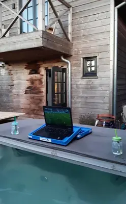 a laptop sitting on a table next to a swimming pool at Maas Lodge in Maaseik