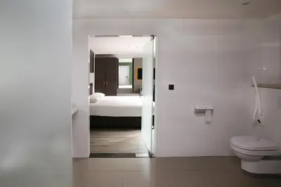 a bathroom with a toilet and a bedroom with a bed at Hotel Au Prince Royal in Leopoldsburg