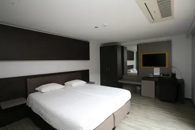 a bedroom with a white bed and a television at Hotel Au Prince Royal in Leopoldsburg