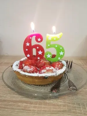 a birthday cake with a candle on a table at B&B Le Jardin in Pelt