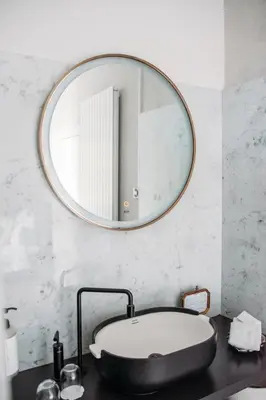 a bathroom with a large round mirror above a tub at B&B Maison Mairie Hasselt in Hasselt