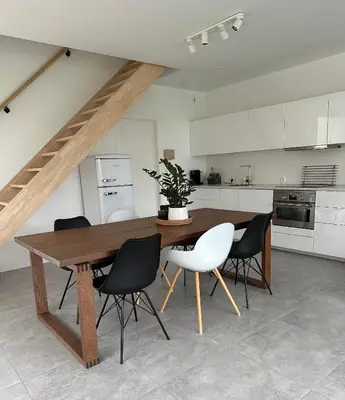 a kitchen with a wooden table and black and white chairs at Domum in Dilsen-Stokkem