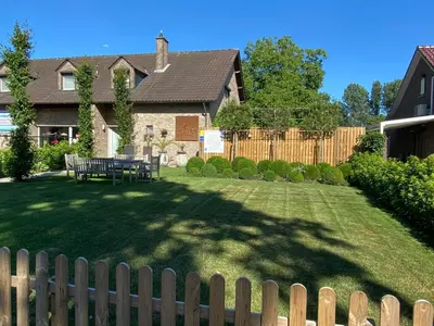 a backyard with a wooden fence and a table in the yard at Vakantiewoning Het Wielje Maasland in Kinrooi