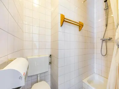 a white tiled bathroom with a toilet and a shower at De Appelgaard Voeren Estate in Berg