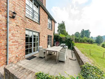 a patio with a table and chairs next to a brick building at De Appelgaard Voeren Estate in Berg