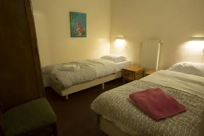 a hotel room with two beds and a chair at Apartments Cour d'Aix in Richelle