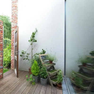 a patio with potted plants on a wooden deck at Hotel Restaurant Vous lé Vous in Hasselt