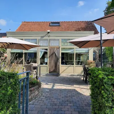 a patio with chairs and umbrellas in front of a house at B&B Kerkevelde in Bilzen