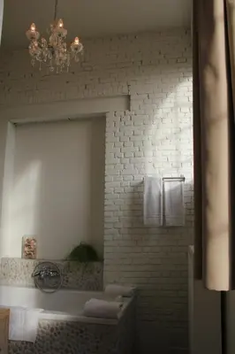 a bathroom with a mirror and a white brick wall at B&B Amuse-Couche in Hasselt