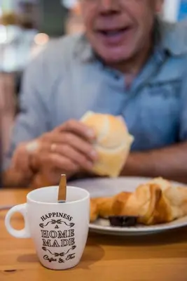 a man sitting at a table with a plate of breakfast food at B&B De Kroonhoeve in Beringen