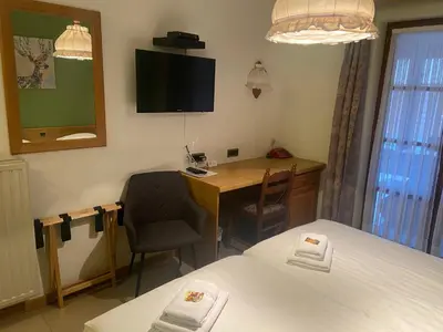 a room with a desk and a bed and a table and chair at Hotel Monika in Zutendaal