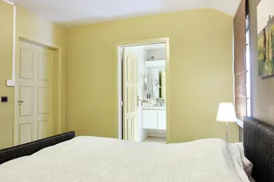 a bedroom with a white bed and a bathroom at Pieters Huis in Kinrooi