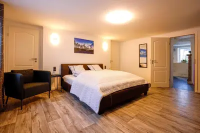 a bedroom with a bed and a chair at Marias Guest House in Eynatten
