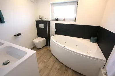 a bathroom with a white tub and a toilet at Marias Guest House in Eynatten
