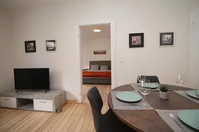 a living room with a dining table and a bedroom at Appart Nicolas in Eupen