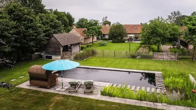 a chair and an umbrella next to a pond at 1 Bed Villa - Sleeps 2 - Garden - Parking - Wifi in Grote-Brogel