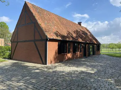 a large brick building with a rusty roof at Drieskenshoeve in Grote-Brogel
