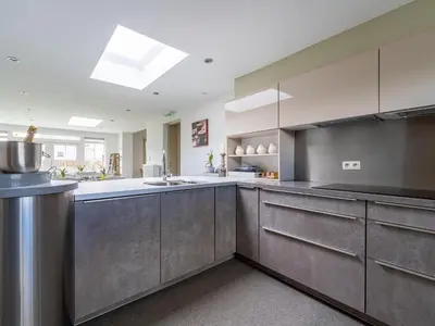a large kitchen with stainless steel cabinets and a sink at Secretarishuis in Peer