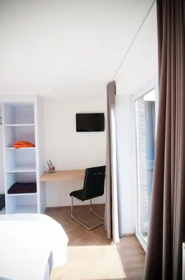a bedroom with a bed and a desk and a window at Apartment De Maasnacht in Maaseik