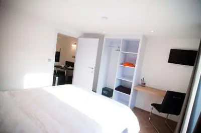 a bedroom with a white bed and a television at Apartment De Maasnacht in Maaseik