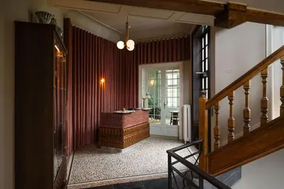a hallway with a room with a table and a staircase at Landgoed Altenbroek in Voeren