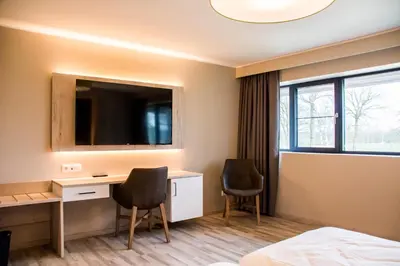 a hotel room with a desk and a tv at De Zwaluwhoeve in Peer