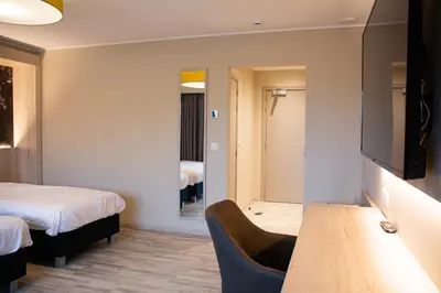 a room with two beds and a table and a tv at De Zwaluwhoeve in Peer