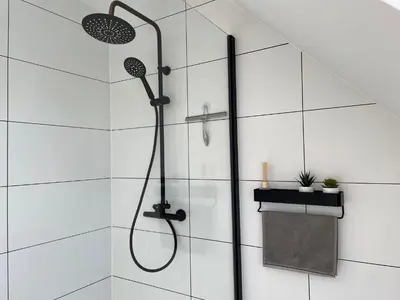 a shower in a bathroom with white tiles at Vakantiehuis Sahara119 in Lommel