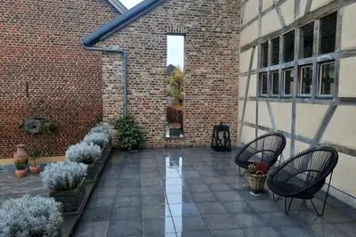 an outdoor patio with two chairs and potted plants at Hof van Eggertingen Bakhuis in Riemst