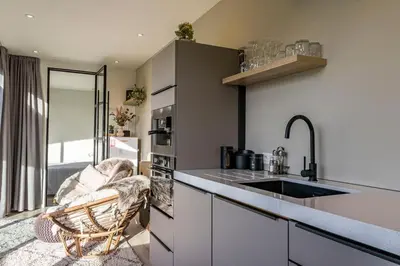 a kitchen with a sink and a counter with a chair at De Hoeveschuur in Riemst